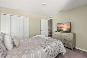Un dormitorio con cama, cómoda, televisor y armario.