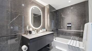 Un baño moderno con un espejo grande, una bañera y una ducha.