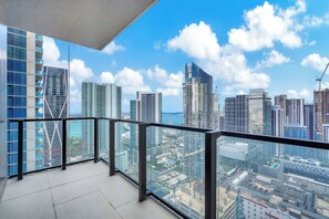 Um edifício alto com varanda de vidro e vista para a cidade.