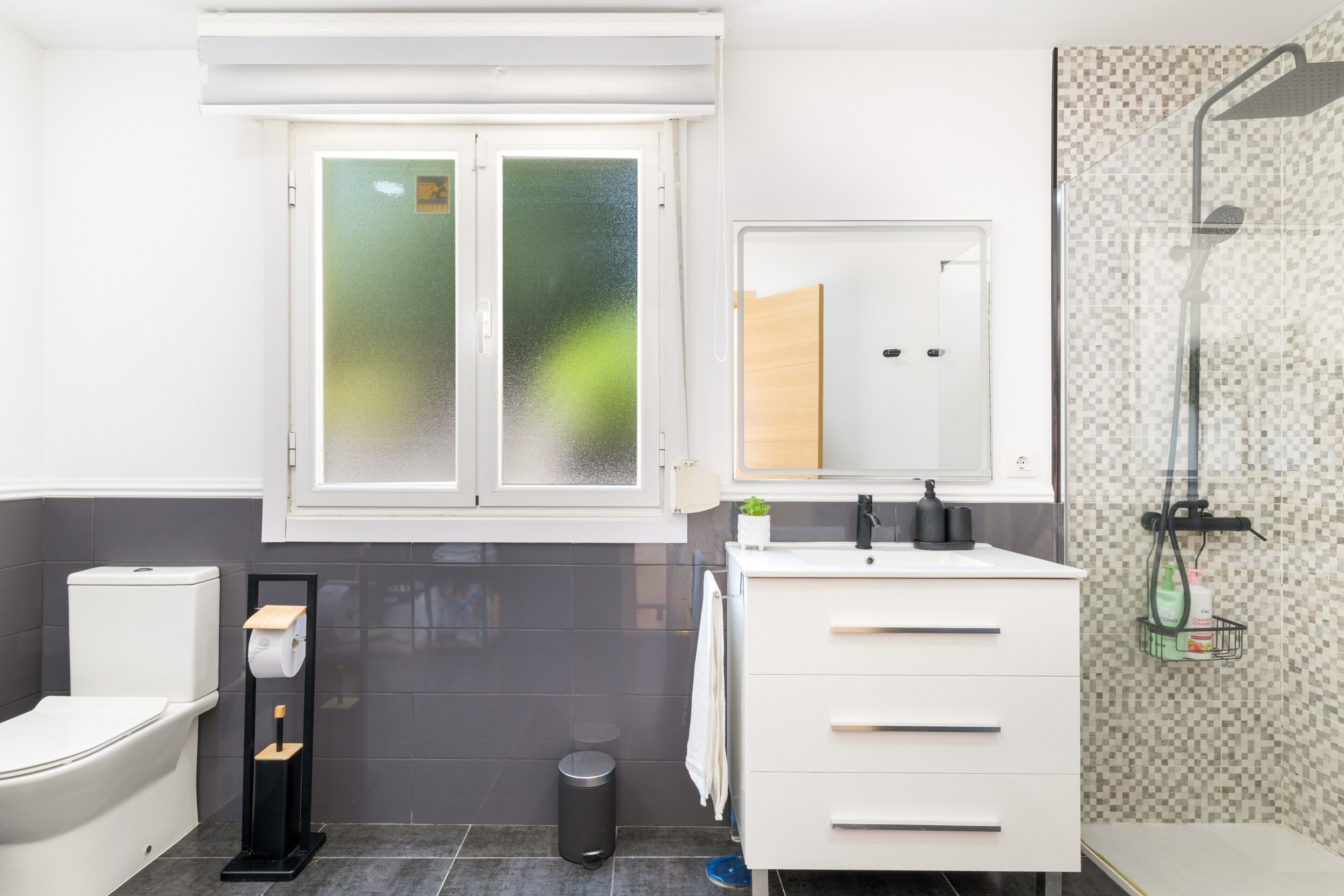 Un baño moderno con inodoro, bidé, tocador, espejo y ducha.