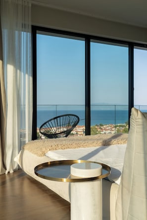 Ein Schlafzimmer mit großem Fenster, einem Bett, einem runden Tisch und einem Stuhl.
