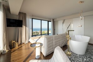 Une chambre d’hôtel moderne dotée d’une grande fenêtre, d’une baignoire blanche, d’un canapé et d’un téléviseur à écran plat.