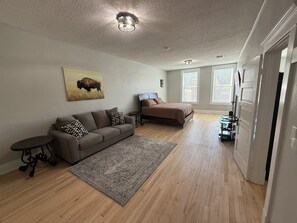 A spacious room with a large bed, a sofa, a small table, and a rug.