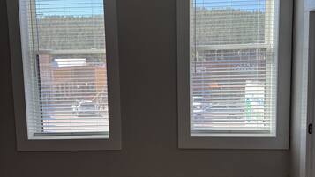 A room with two windows, a wooden floor, and a door.
