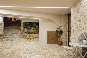 A stone-floored courtyard with a staircase, a potted plant, and a table with chairs. - Villa Methorion Manor - With Private Pool (Saitoures)