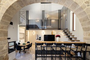 A modern interior with a dining area, a TV, and a staircase. - Villa Methorion Manor - With Private Pool (Saitoures)