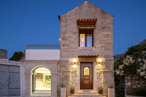 A stone building with a wooden door, an archway entrance, and a small balcony. - Villa Methorion Manor - With Private Pool (Saitoures)