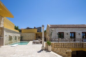 A courtyard with a swimming pool, lounge chairs, and a stone building with a tiled roof. - Villa Methorion Manor - With Private Pool (Saitoures)