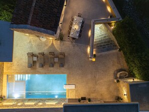 An aerial view of a rooftop pool area with a sun terrace, lounge chairs, and a dining set. - Villa Methorion Manor - With Private Pool (Saitoures)
