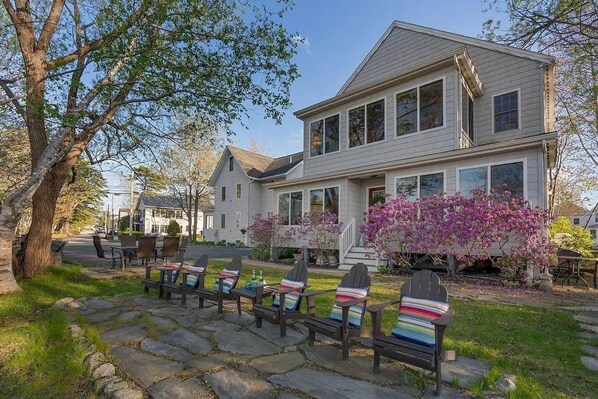 A two-story house with a stone pathway leading to outdoor seating.