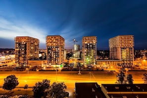 A high-rise building complex with multiple floors, a construction crane, and a well-lit parking area. - LILY APART Obrońców Wybrzeża by the sea (Gdańsk)