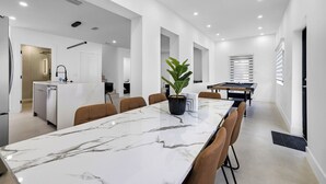 Een moderne keuken met een inbouwvaatwasser, een eethoek met een marmeren tafel en een pooltafel.
