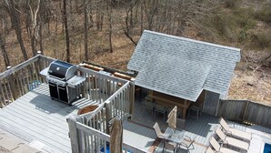 Una terraza con parrilla, mobiliario exterior y una piscina.