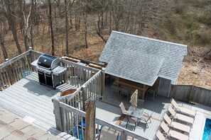 Eine Terrasse mit Grill, Sitzgelegenheiten und einem Pool.