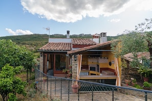A rustic house with a stone exterior, a tiled roof, and a fenced patio area with potted plants. - La Cabaña del Llano — private pool and garden on an Extremaduran estate, near Portugal (La Aceña de la Borrega)