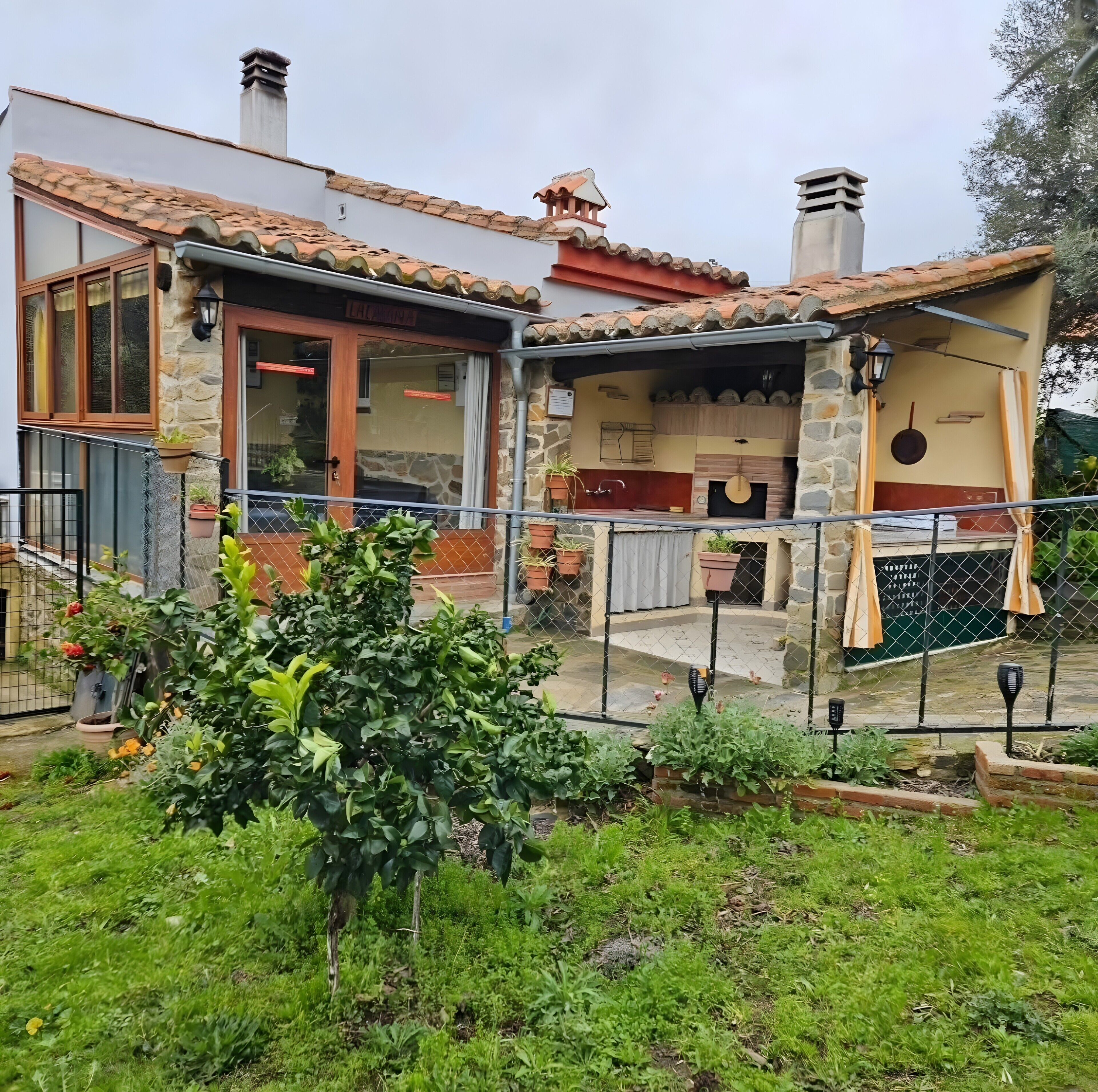 A stone building with a tiled roof, a wooden door, and a small outdoor kitchen area.