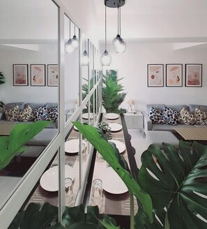 A modern dining area with a glass partition, a staircase, and a sofa with patterned cushions. - Safe Haven Azure Staycation (Parañaque)