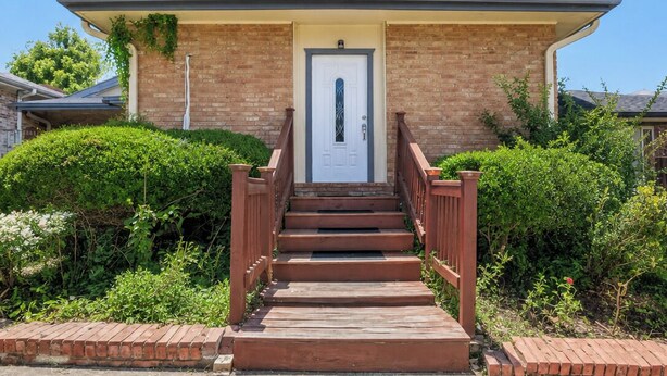 A two-story house with a front porch, a door, and a staircase leading to the entrance.