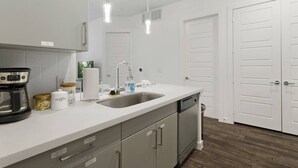 Een moderne keuken met een vaatwasser, koffiezetapparaat en opslagkastjes.