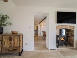 Una sala de estar con chimenea, un televisor montado en la pared y un mueble de madera con una planta.