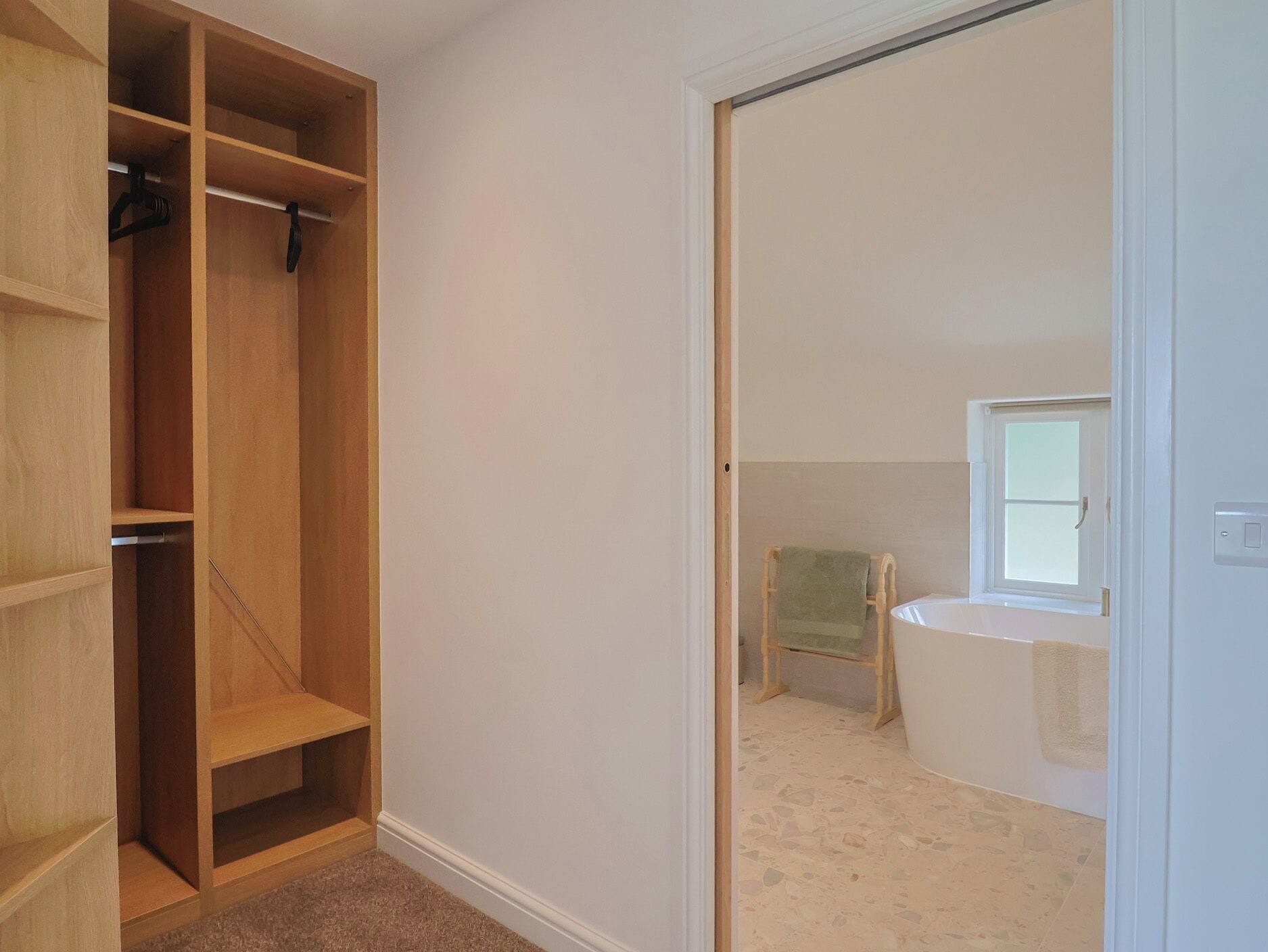 A room with a wooden closet, a small chair, and a bathtub.