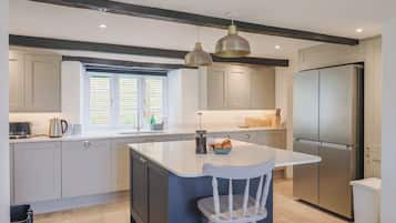 A modern kitchen with a central island, stainless steel appliances, and a window with blinds.