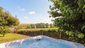 A hot tub in a garden with a wooden fence and trees.