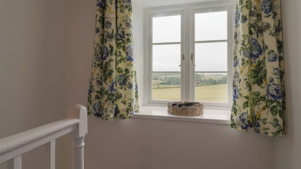 A room with a window, white walls, and a white railing.