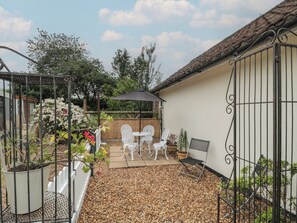A patio with a table and chairs, surrounded by potted plants and a white fence. - Little Herriotts (Bristol)
