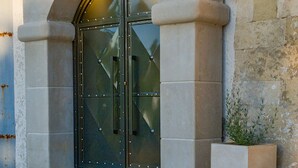 A building with a large arched entrance, stone steps, and a planter box. - Villa Methorion Manor - With Private Pool (Rethymno)