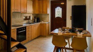 A kitchen with wooden cabinets, a dining table with chairs, a coffee maker, and a door with a window. - Villa Methorion Manor - With Private Pool (Rethymno)