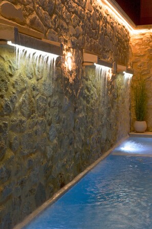 Paredão de pedra com um elemento aquático, incluindo uma piscina e uma cascata.