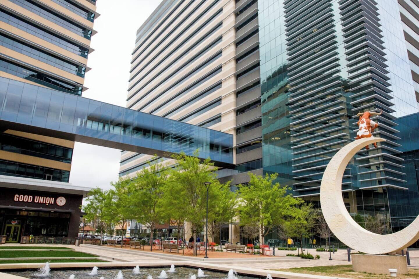 A modern building with a glass facade, a large circular sculpture, and a 'GOOD UNION' sign.