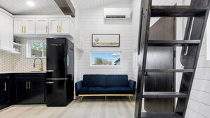 A modern kitchen with white cabinetry, a black refrigerator, and a blue sofa. - Modern Retreat|Tiny House|Weekly&Monthly Discount (Richardson)
