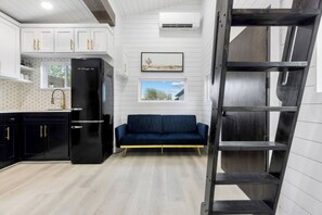 A modern kitchen with white cabinetry, a black refrigerator, and a blue sofa. - Modern Retreat|Tiny House|Weekly&Monthly Discount (Richardson)