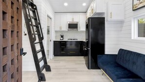 A modern kitchen with white cabinets, a black refrigerator, and a blue sofa. - Modern Retreat|Tiny House|Weekly&Monthly Discount (Richardson)