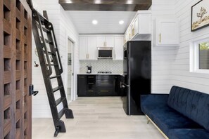 A modern kitchen with white cabinets, a black refrigerator, and a blue sofa. - Modern Retreat|Tiny House|Weekly&Monthly Discount (Richardson)