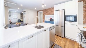 Una cocina moderna con armarios blancos, un refrigerador de acero inoxidable, un microondas y un lavavajillas.