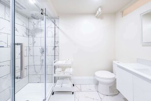 A modern bathroom with a glass-enclosed shower, a toilet, and a white sink. - Near the Ferry | L'Appartement des Notaires (Lévis)