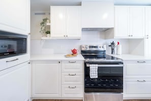 Una cocina moderna con armarios blancos, horno integrado, microondas y estufa.