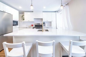 Una cocina moderna con armarios blancos, una isla central e iluminación colgante.