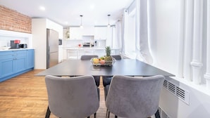Una cocina moderna con armarios blancos, una encimera azul y un comedor con mesa y sillas.