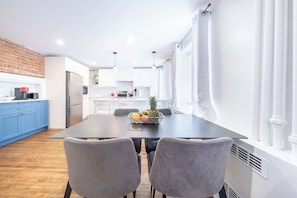 Una cocina moderna con armarios blancos, una encimera azul y un comedor con mesa y sillas.