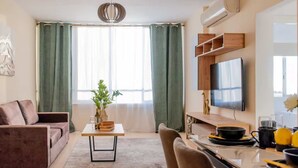 Un saló modern amb un sofà, una taula de dinar, una televisió i una cuina.