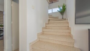 Eine Treppe mit beigen Stufen führt zu einer Empore, auf der sich ein Blumentopf befindet. Darüber an der Wand hängt ein Kunstwerk.