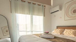Ein Hotelzimmer mit Bett, Stuhl, Spiegel und einem Fenster mit Vorhängen.
