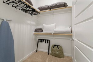 Ein kleiner, weißer Kleiderschrank mit Holzregal, Kleiderstange und einer Tasche.