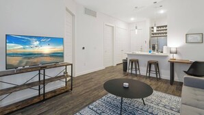 Una sala de estar moderna con un televisor de pantalla plana, una mesita redonda y una alfombra estampada.