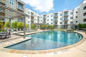 A swimming pool with a sunshade, lounge chairs, and a no diving sign.