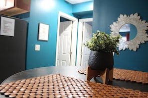 A room with a table covered in round objects, a potted plant, and a wall with a decorative mirror. - New Listing! 1 Bed 1 Bath ny UC/OTR! (Cincinnati)